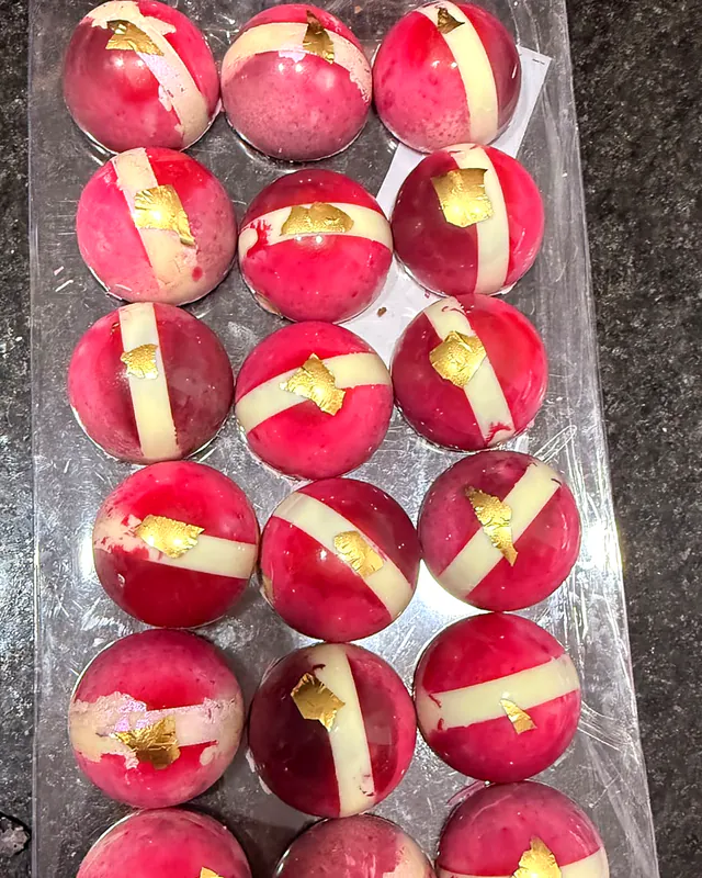 Bombones rosados con franja blanca y hoja de oro