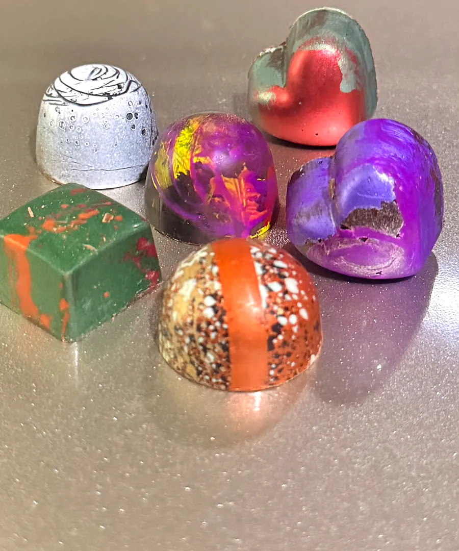 Bombones artesanales de colores: corazones, domos y cuadrados decorados a mano