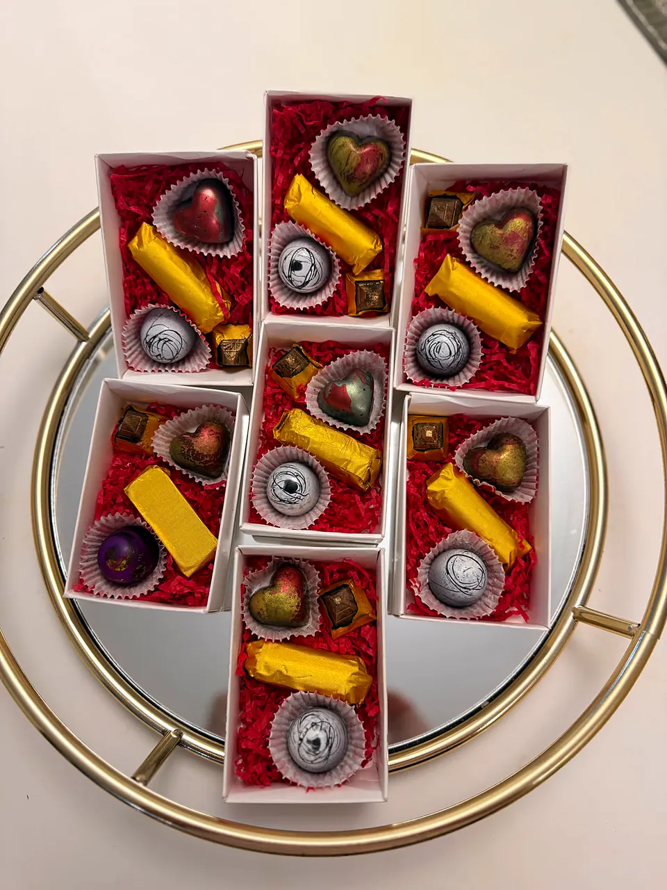 Cajitas de regalo con bombones y barras de chocolate sobre una bandeja dorada
